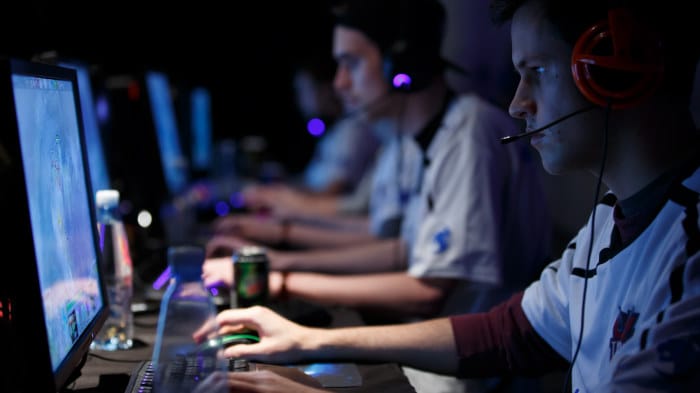A group of people sitting in front of PCs gaming
